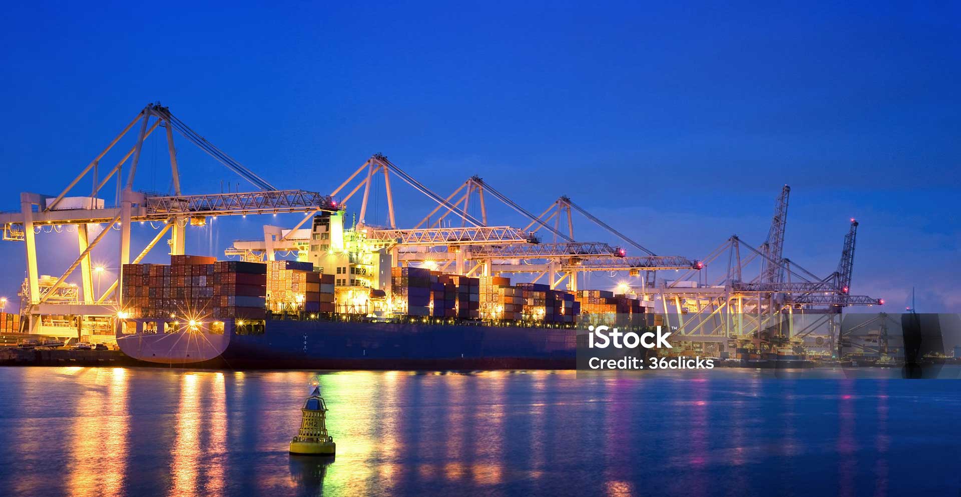 foto di una nave container attraccata presso un terminal in porto. Veduta notturna